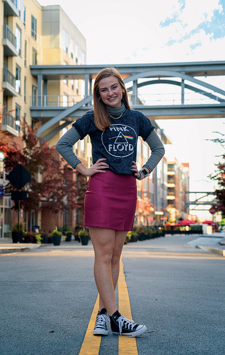 Senior photo of a woman taken on a road in a downtown location.