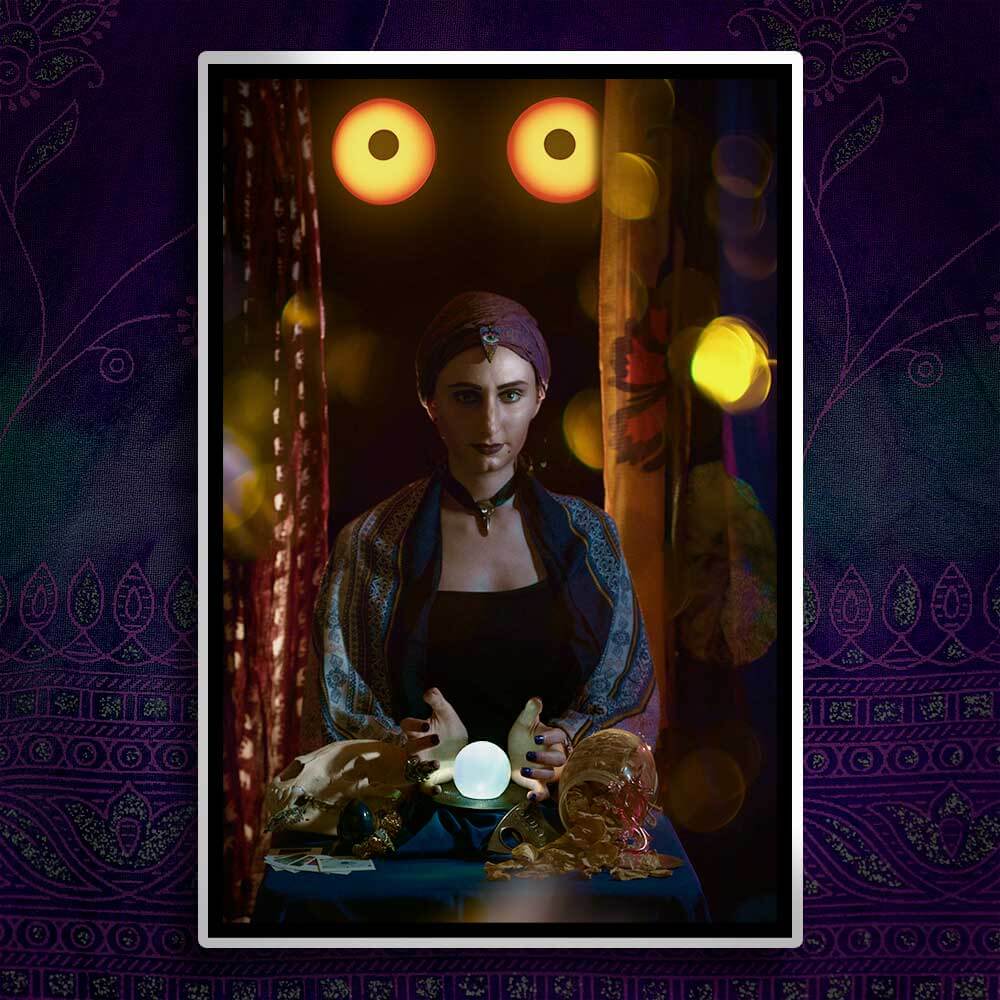 Shot of woman dressed as a forune teller with a crystal ball as glowing eyes wait in the background.