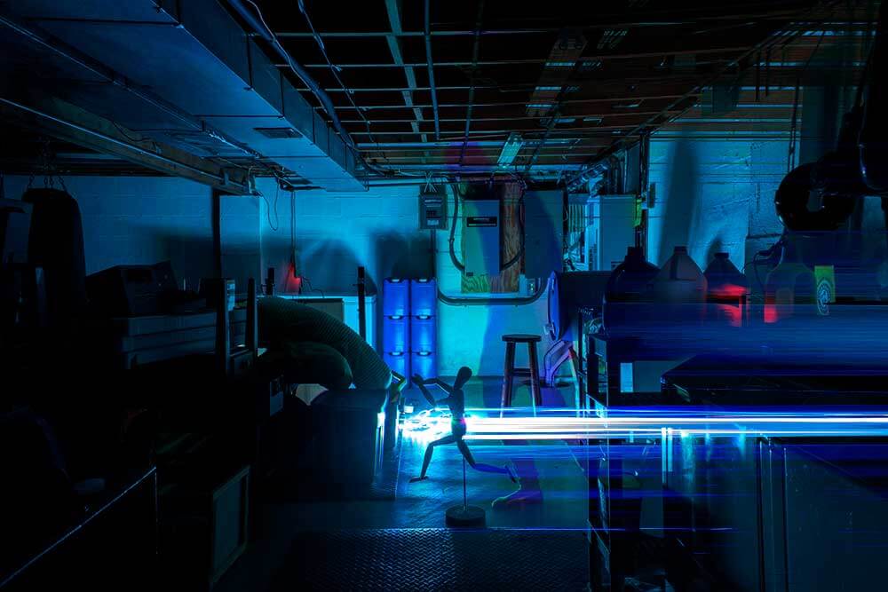 Long exposure of a basement. Lights stretch across the screen and image of a person is partially seen.