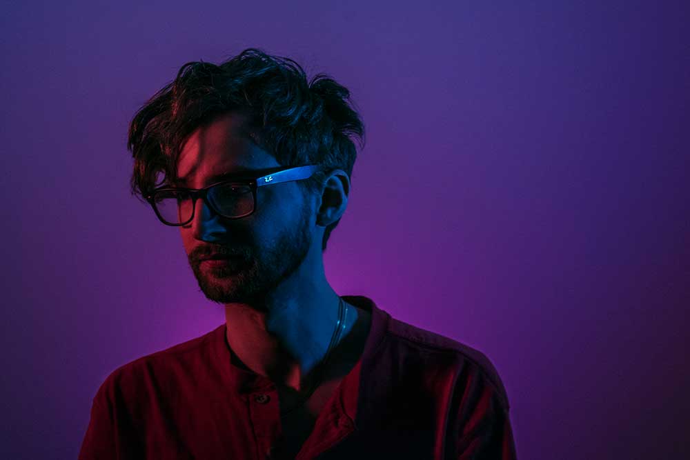 A profile photo of a man in red/blue lighting.