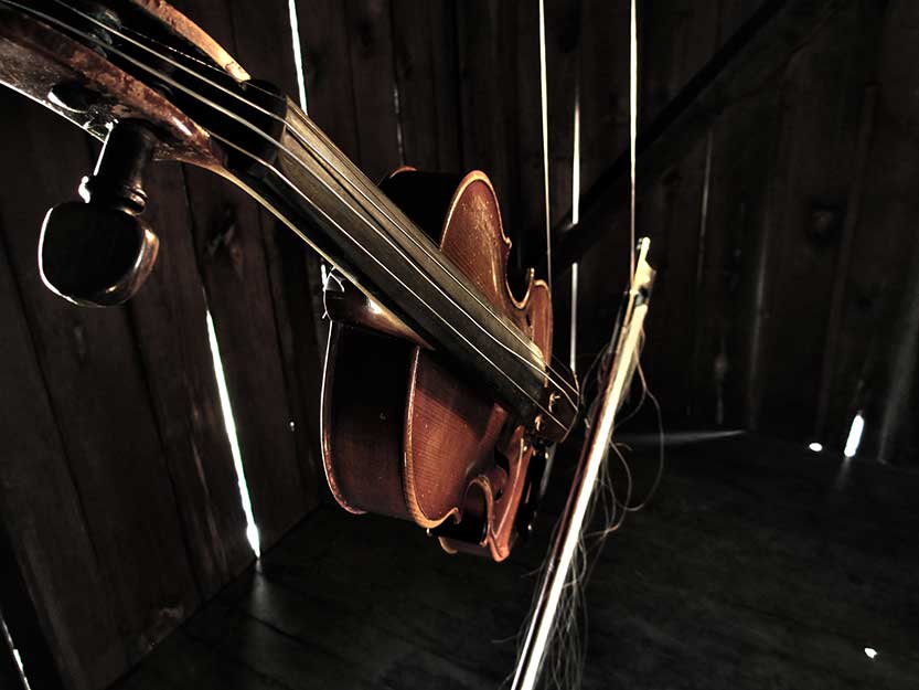 A violin and bow float in an old barn.