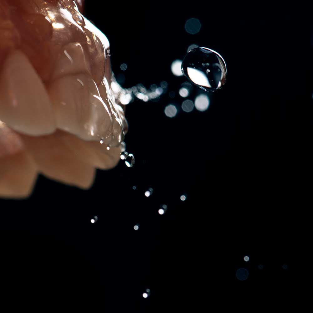 Close up shot of teeth with water droplets on black background.